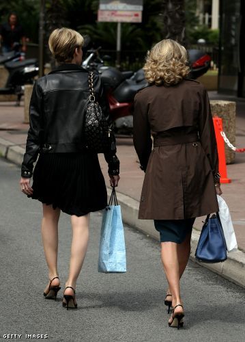 Two women with shopping bags walk down a side street near the Croisette