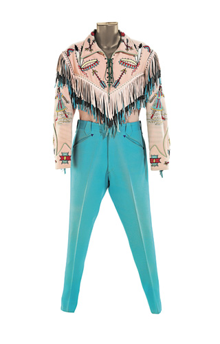 LOT-81 NUDIE THE RODEO TAILOR A pink and turquoise gabardine ensemble made by Nudie for Roy, comprising a lace-up top with a Native American theme, embroidered headdresses on the pink, black and blue leather fringed yoke, female Native Americans embroidered on the sleeves and arrows on the pearl butt
